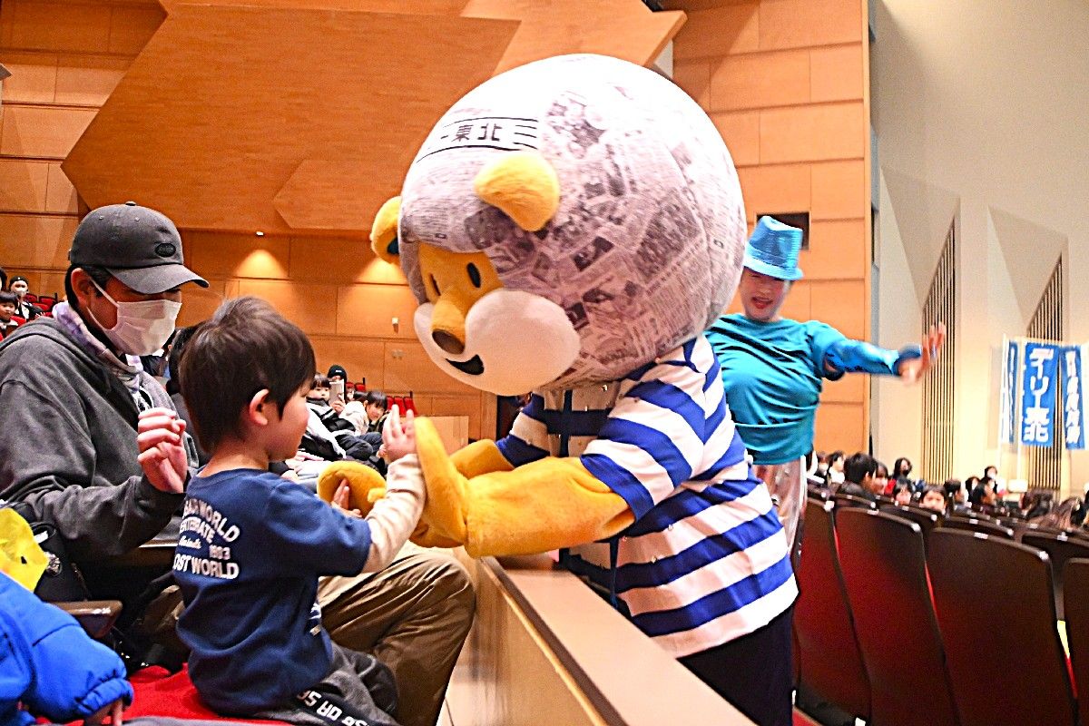 来場者とハイタッチを交わすデリオン=15日、八戸市