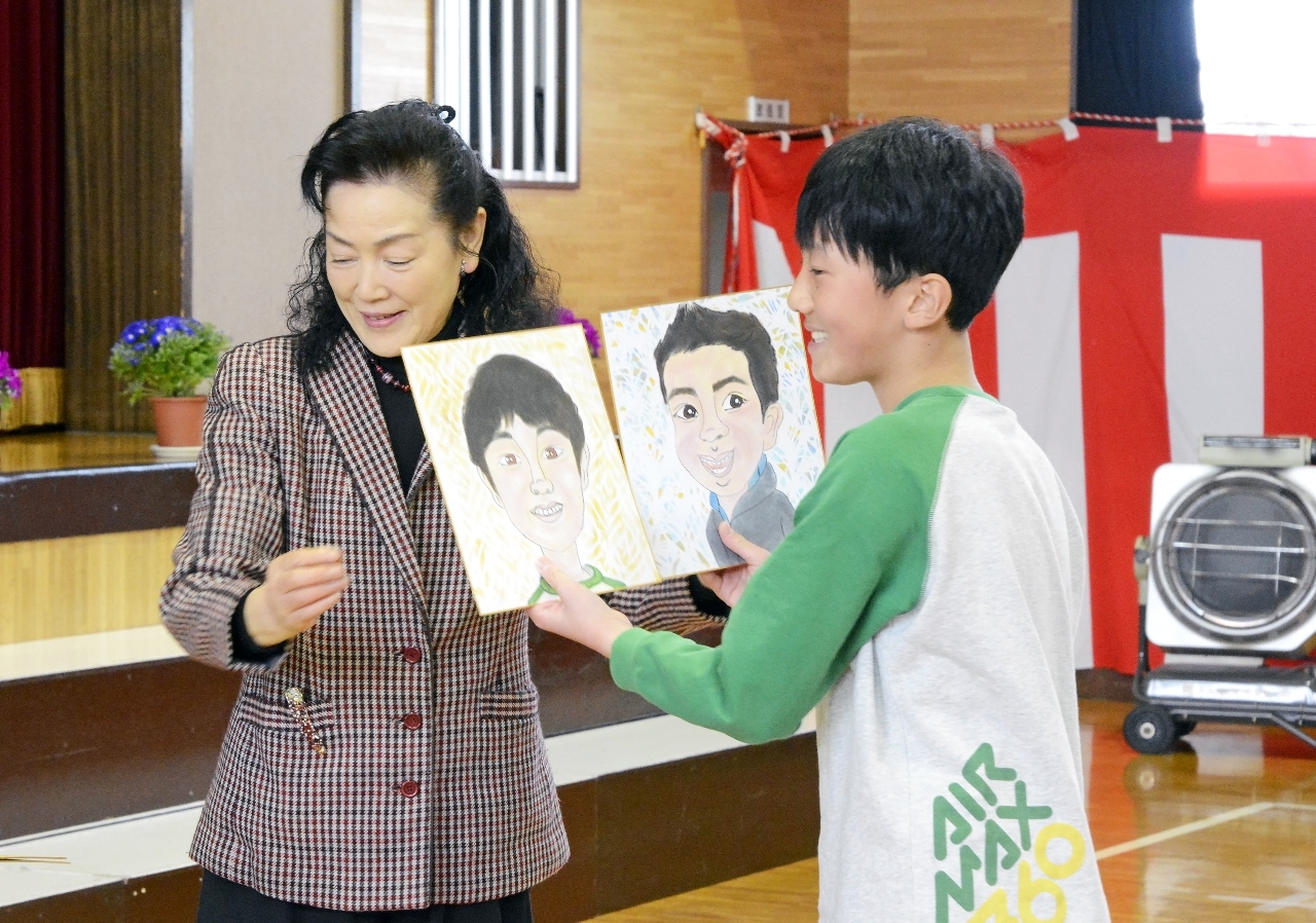 階上友子さん(左)から似顔絵を受け取る児童
