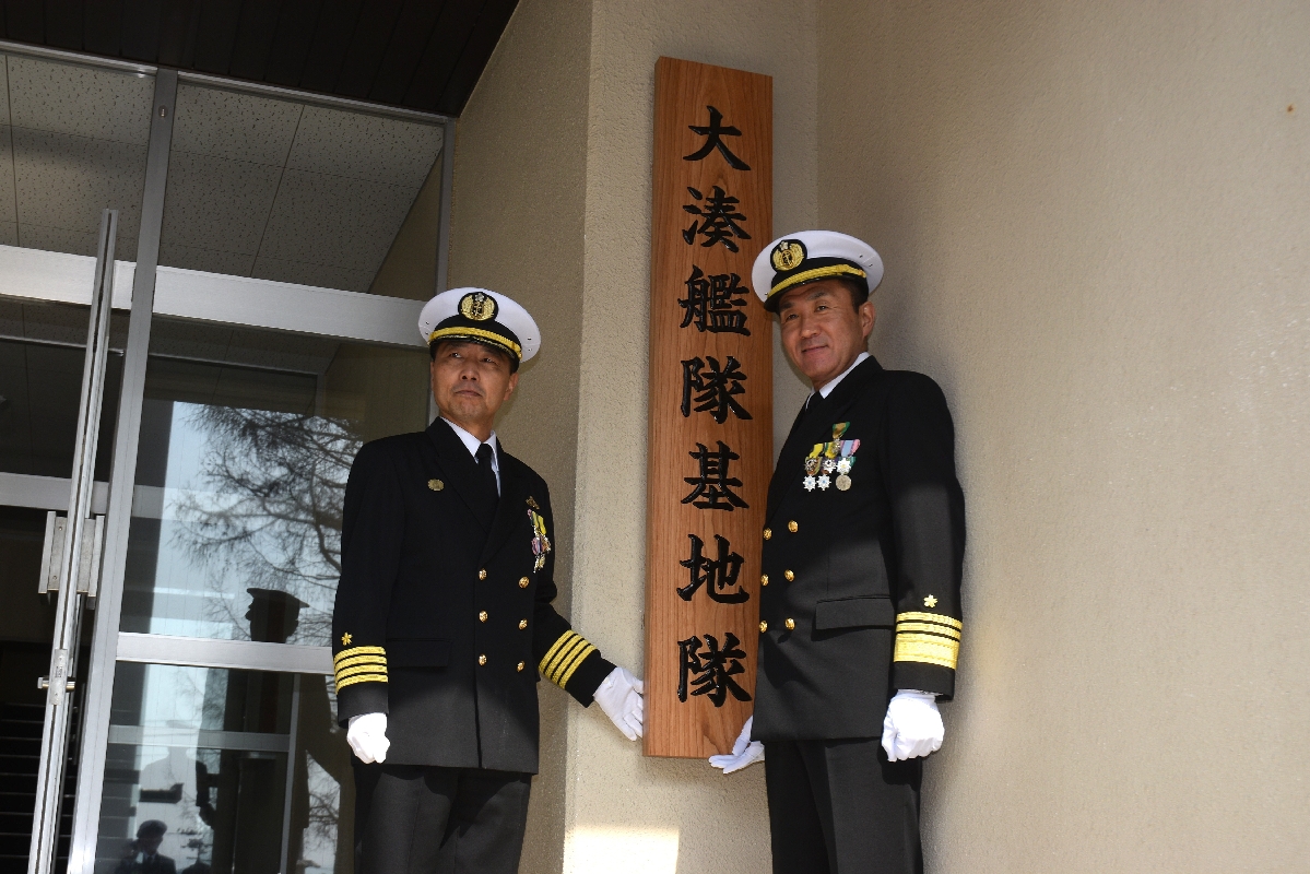 大湊艦隊基地隊の看板を掛け替える稲田丈司総監（右）と天野晋介１等海佐＝２３日、むつ市