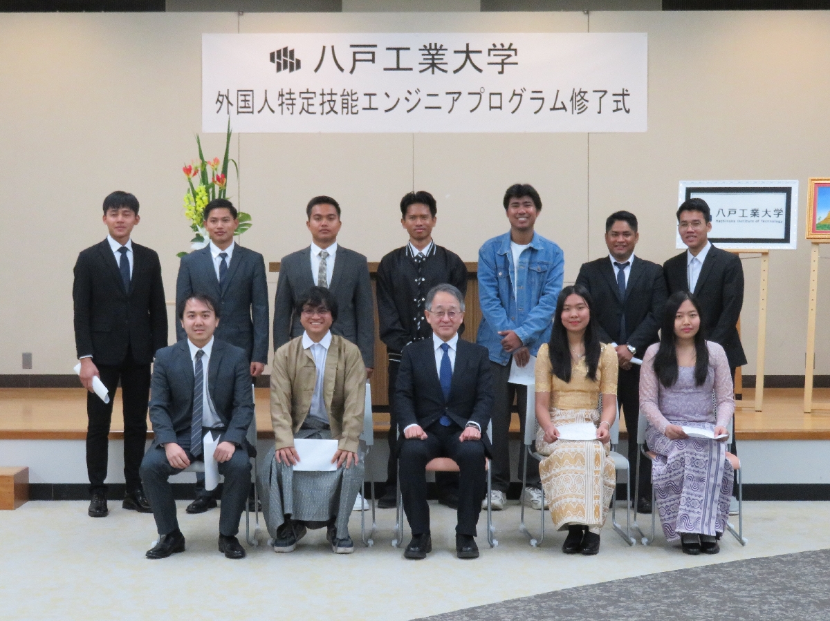 船﨑健一学長(前列中央)から修了証を授与されたミャンマー人の留学生=23日、八戸市(八戸工業大提供)