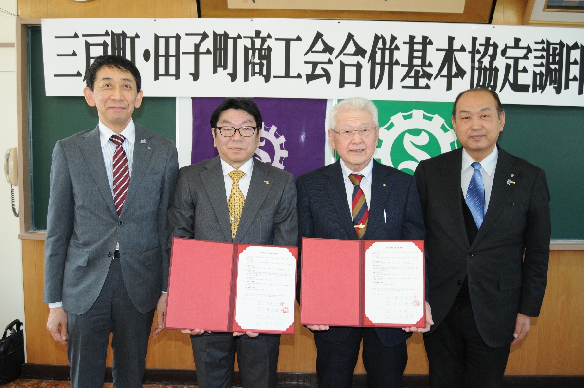 合併基本協定に調印した釜澤英文会長（左から２人目）と井畑博明会長（同３人目）＝２５日、三戸町