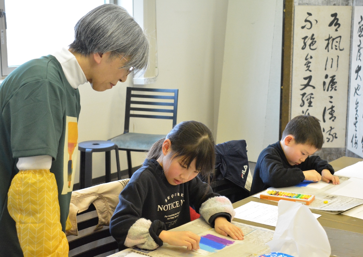 柳田眞理子さん(左)から色塗りのこつを教わる参加者