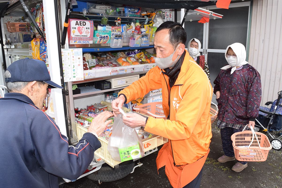 移動スーパー「とくし丸」を運行する杉山政司さん(中央)。買い物弱者のため使命感を持って働いている=4月30日、八戸市南郷中野下洗