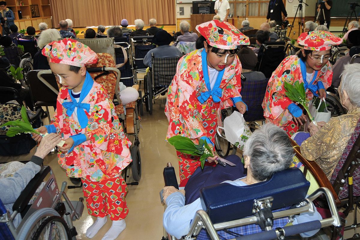 高齢者にスズランを贈る旧小国小の児童。少子化による小学校の閉校で心温まる活動もなくなった=2017年5月、久慈市山形町