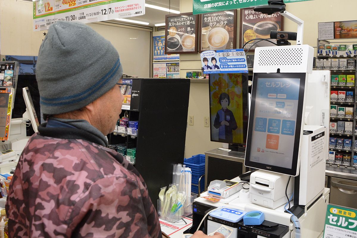 アバター店員の接客を受けながらセルフレジを利用する買い物客。人手不足を補う一助になっている=11月下旬、十和田市