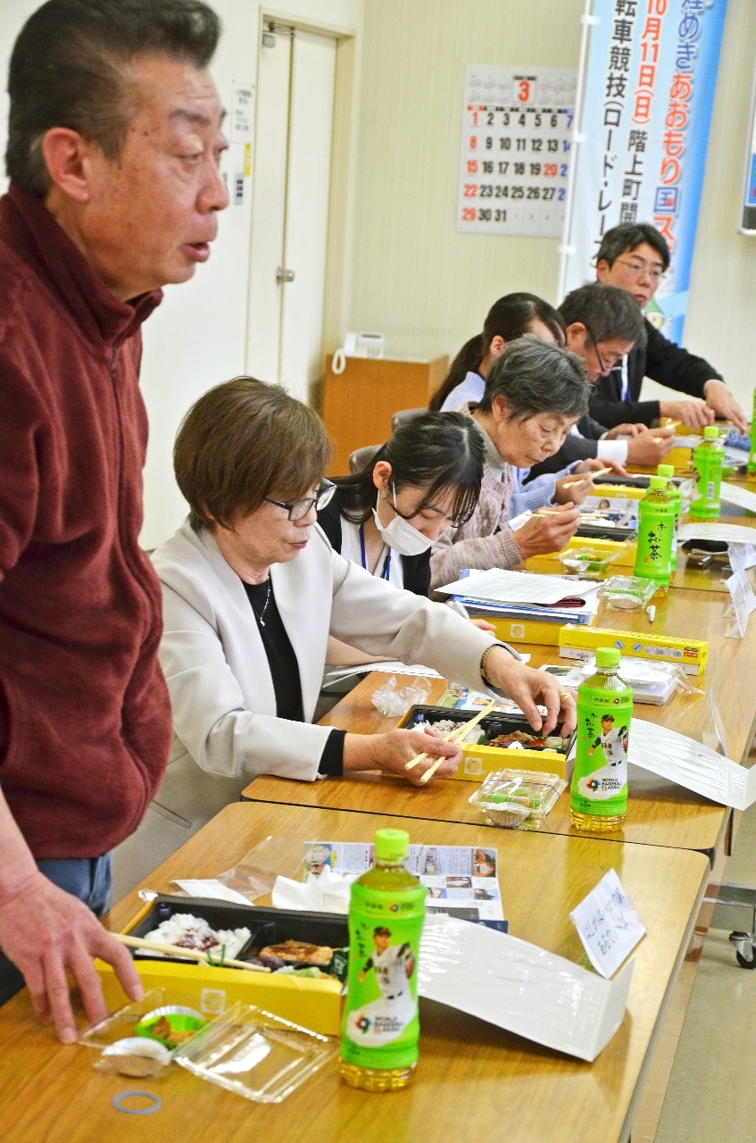 島守敦料理長(手前)の説明を受けながら弁当を試食する出席者