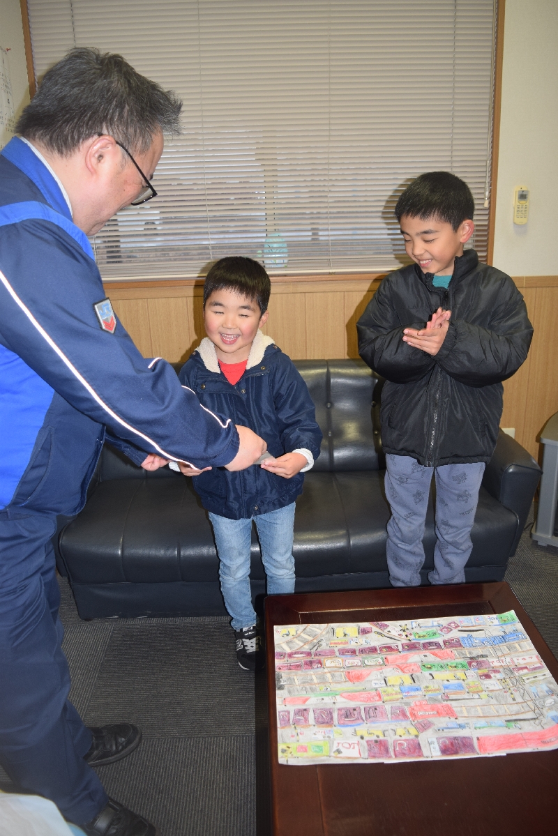 柿崎秀太駅長(左)から感謝状を贈られる佐藤広平ちゃん(中央)。兄の正平さんも拍手で祝った