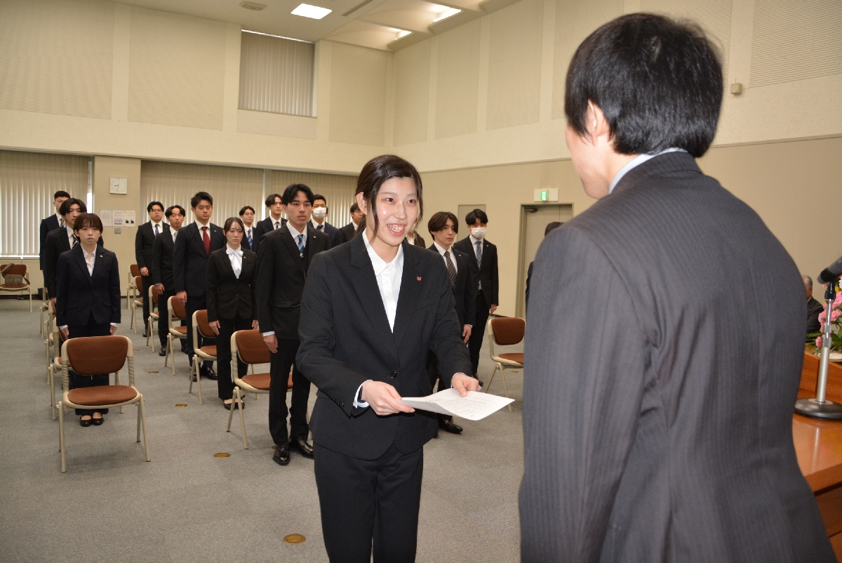 吉田昌弘社長（右）から辞令交付を受け笑顔を見せる髙橋沙月さん＝１日、八戸市