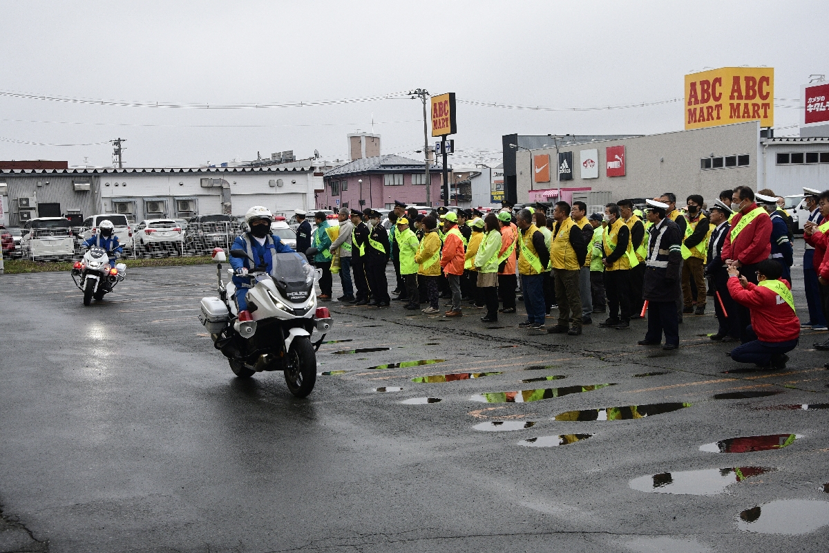 出動する警察車両を見守る関係者