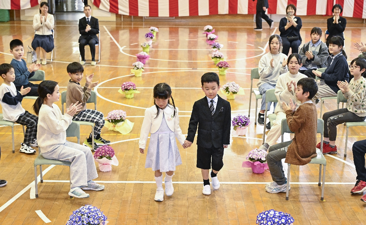 在校生に拍手で迎えられる新入生=7日、八戸市立豊崎小学校