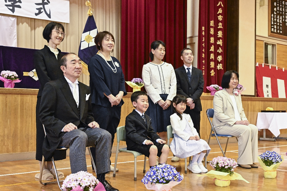 保護者や担任の先生とともに、記念撮影に臨む新入生＝７日、八戸市立豊崎小学校