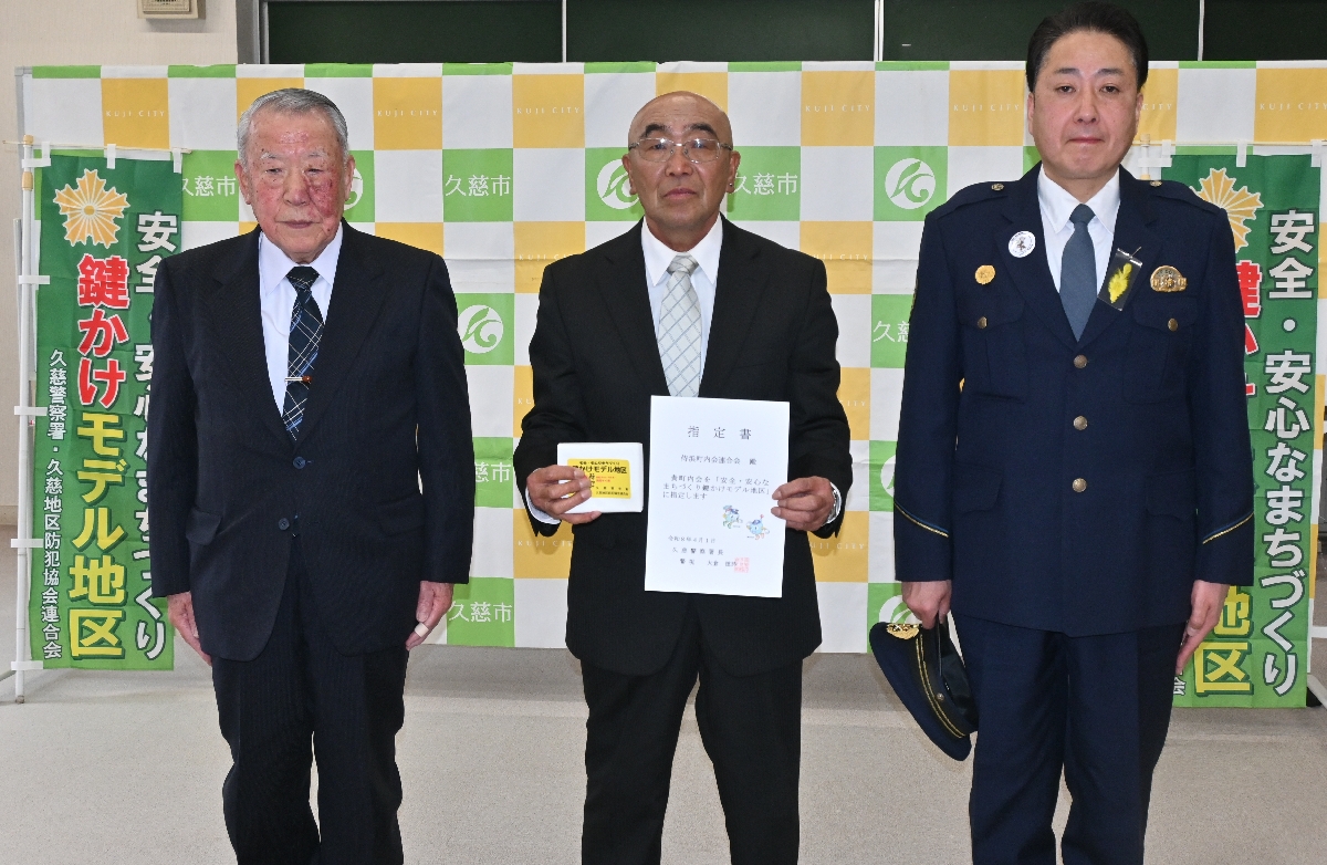 鍵かけモデル地区指定書を手にする侍浜町内会連合会の船渡建治理事(中央)。右は大倉德詩署長、左は三船進一副会長