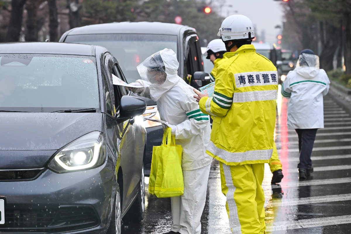 市官庁街通りの横断歩道前でドライバーに交通安全を喚起するチラシを配る十和田署員ら