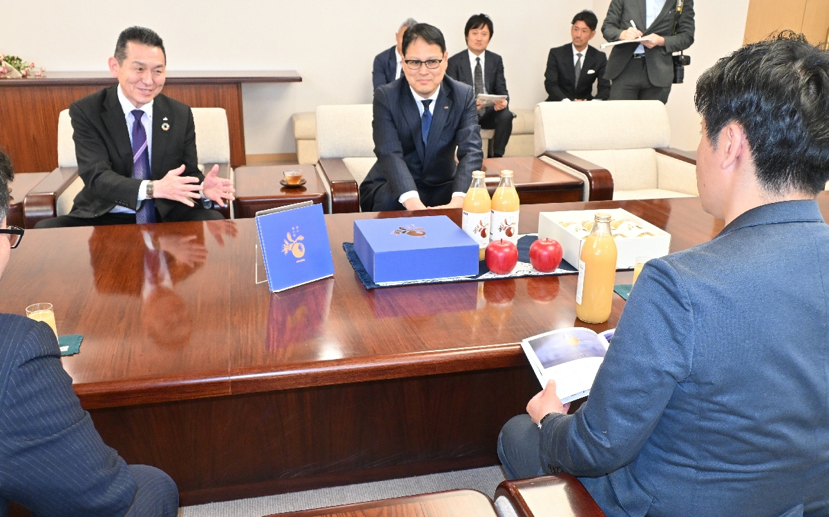 宮下宗一郎知事（手前右）に商品を説明する小笠原康彦会長（奥左）と稲垣慶一マーケティング本部長＝１６日、青森県庁