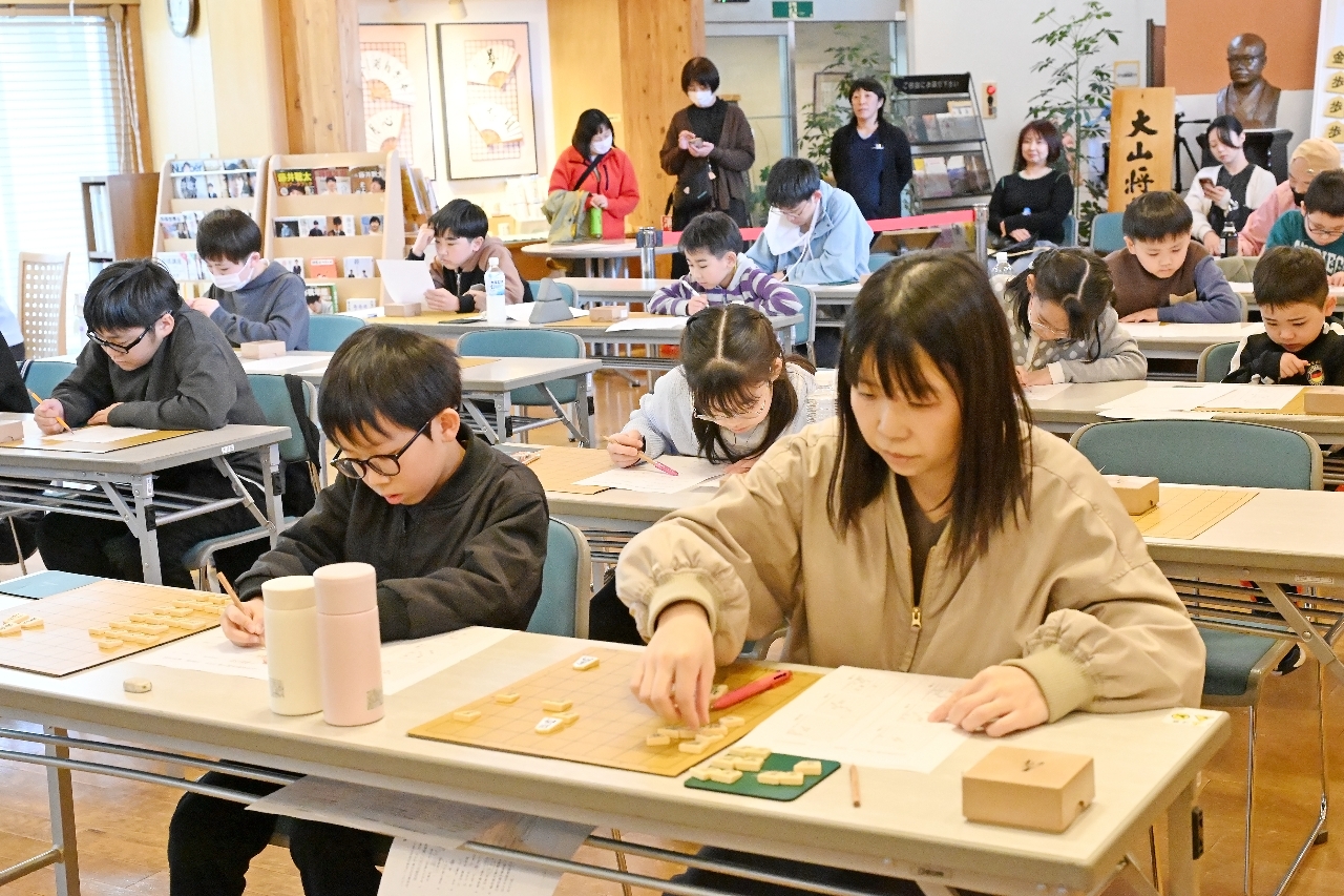 真剣な表情で詰め将棋に挑戦する参加者