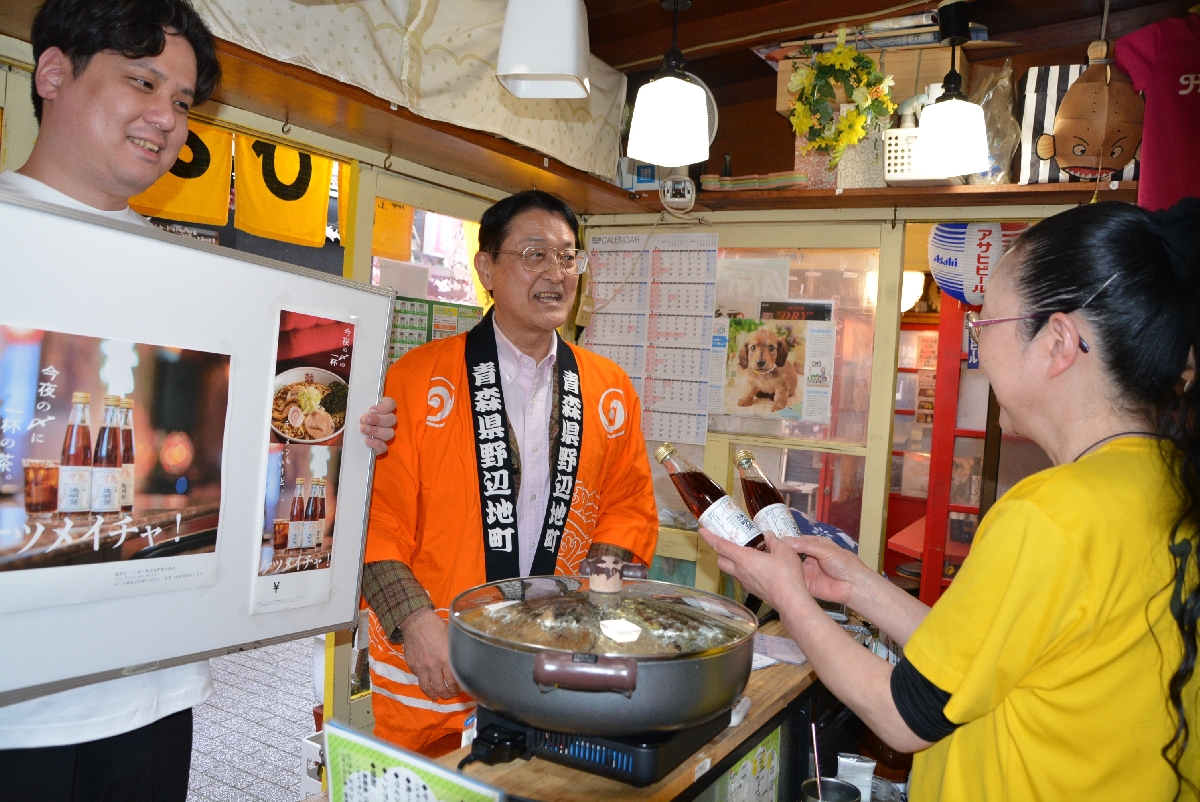 みろく横丁の飲食店で新商品「決明茶」をＰＲする野辺地町の野村秀雄町長（中央）と上野実さん（左）＝１７日、八戸市