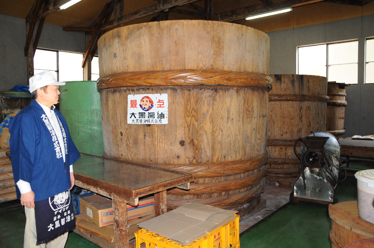 高さ2メートルほどのみそだる。この中で1年以上かけじっくり熟成させる。左は坂本剛さん