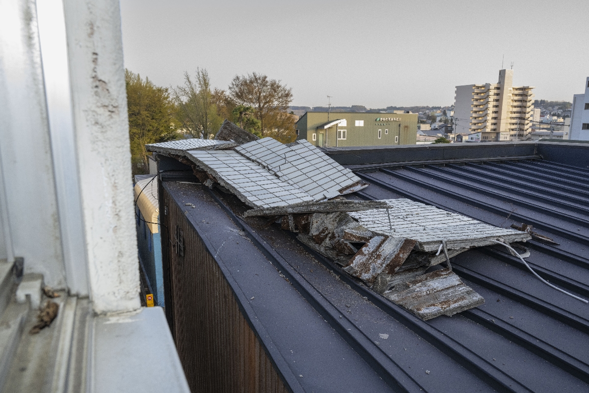 壁面が崩落し、隣のビルに散乱したタイル=20日午後5時半すぎ、八戸市廿三日町
