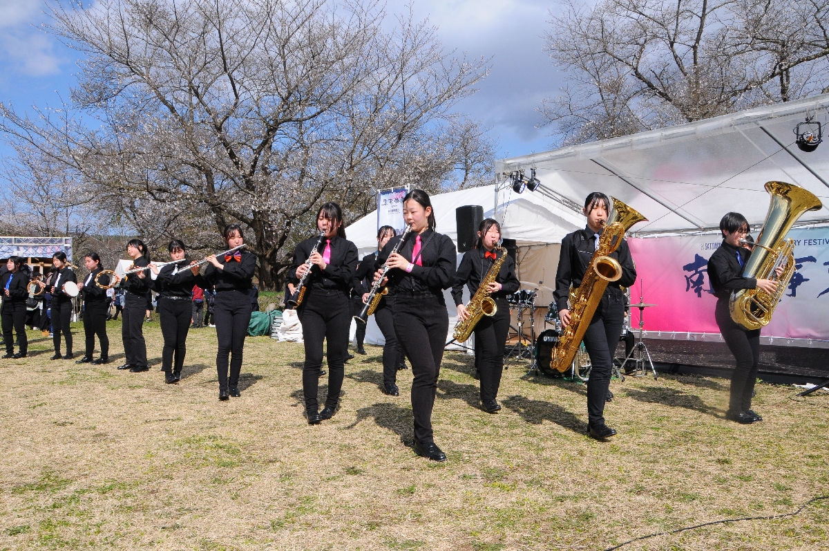 桜が咲く本丸の会場で演奏を披露する北桜高吹奏楽部