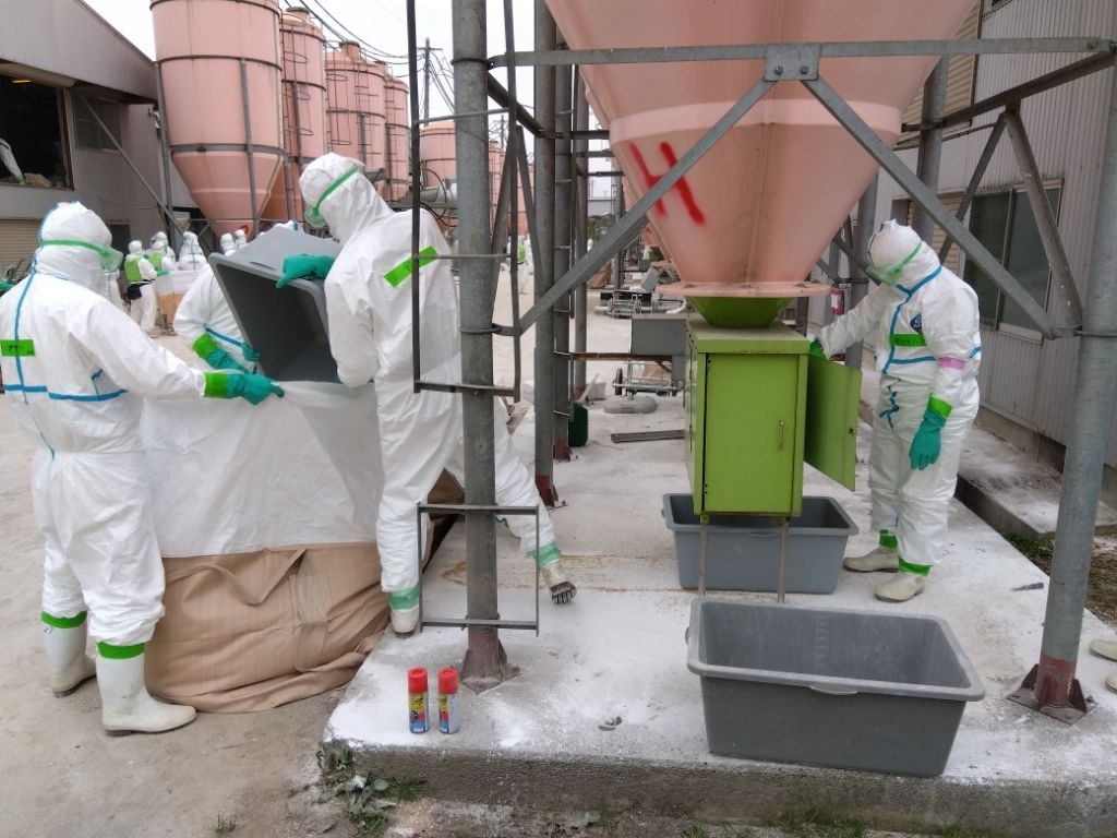 養鶏場で飼料の搬出作業に当たる職員ら=27日、東北町(青森県提供)