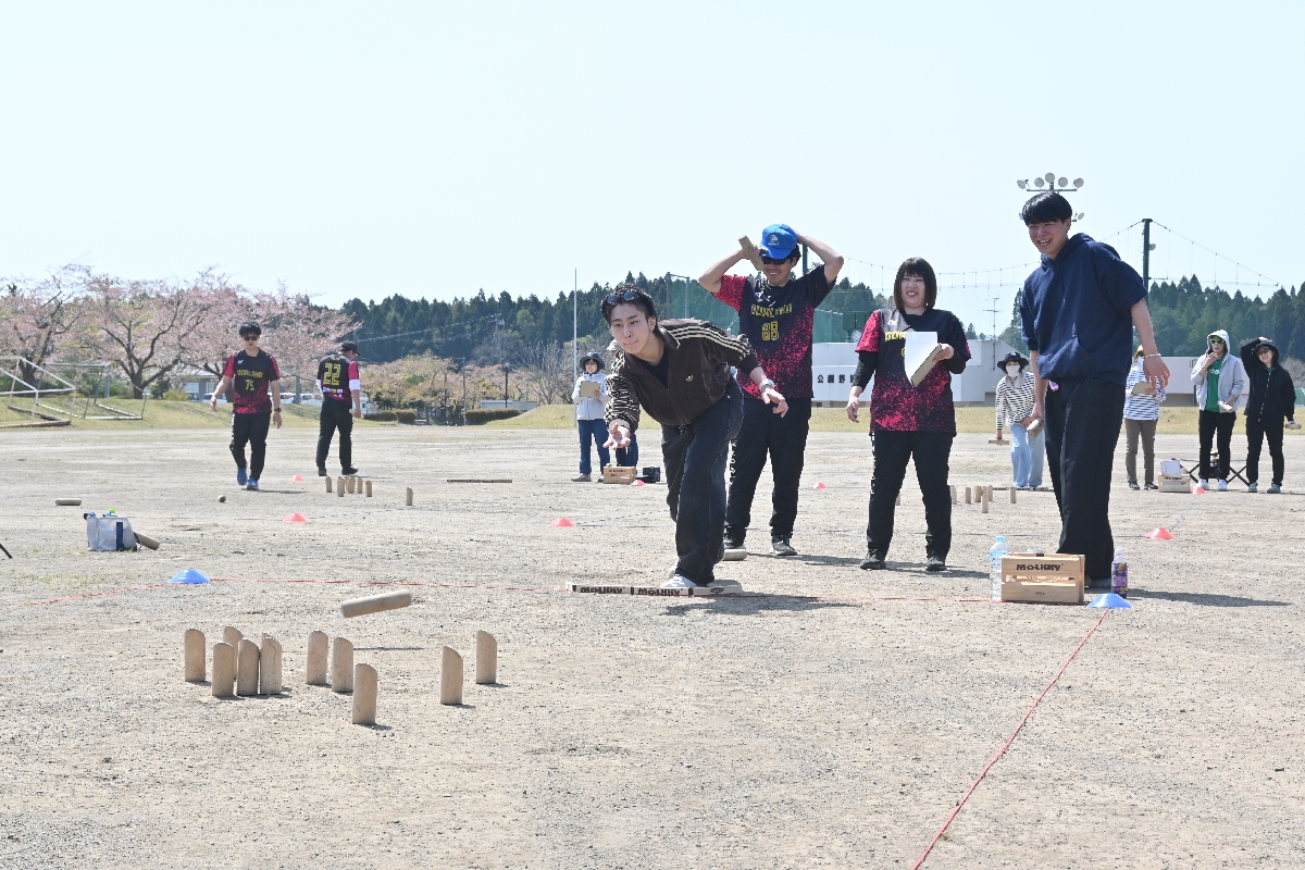 ピンに狙いを定めて棒を投げる選手