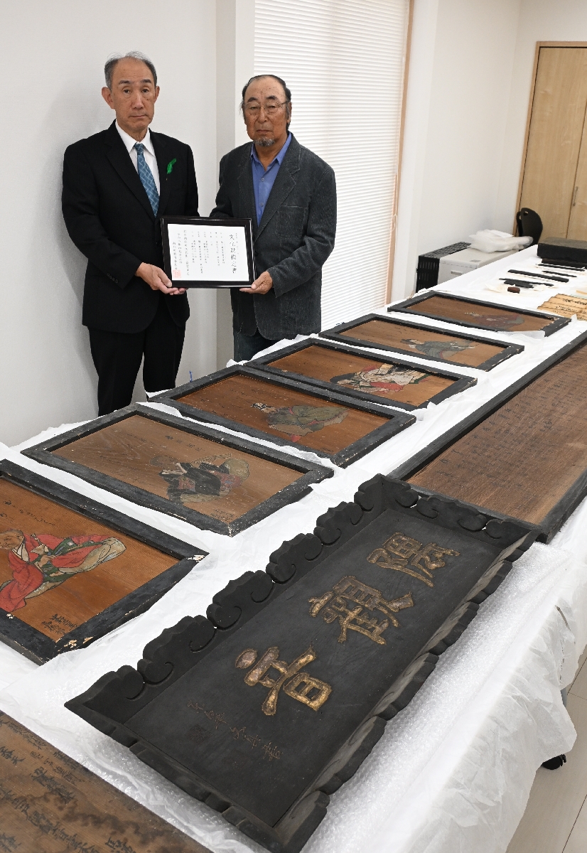 南部町文化財の指定書を手にする堀内重男さん（右）と資料群