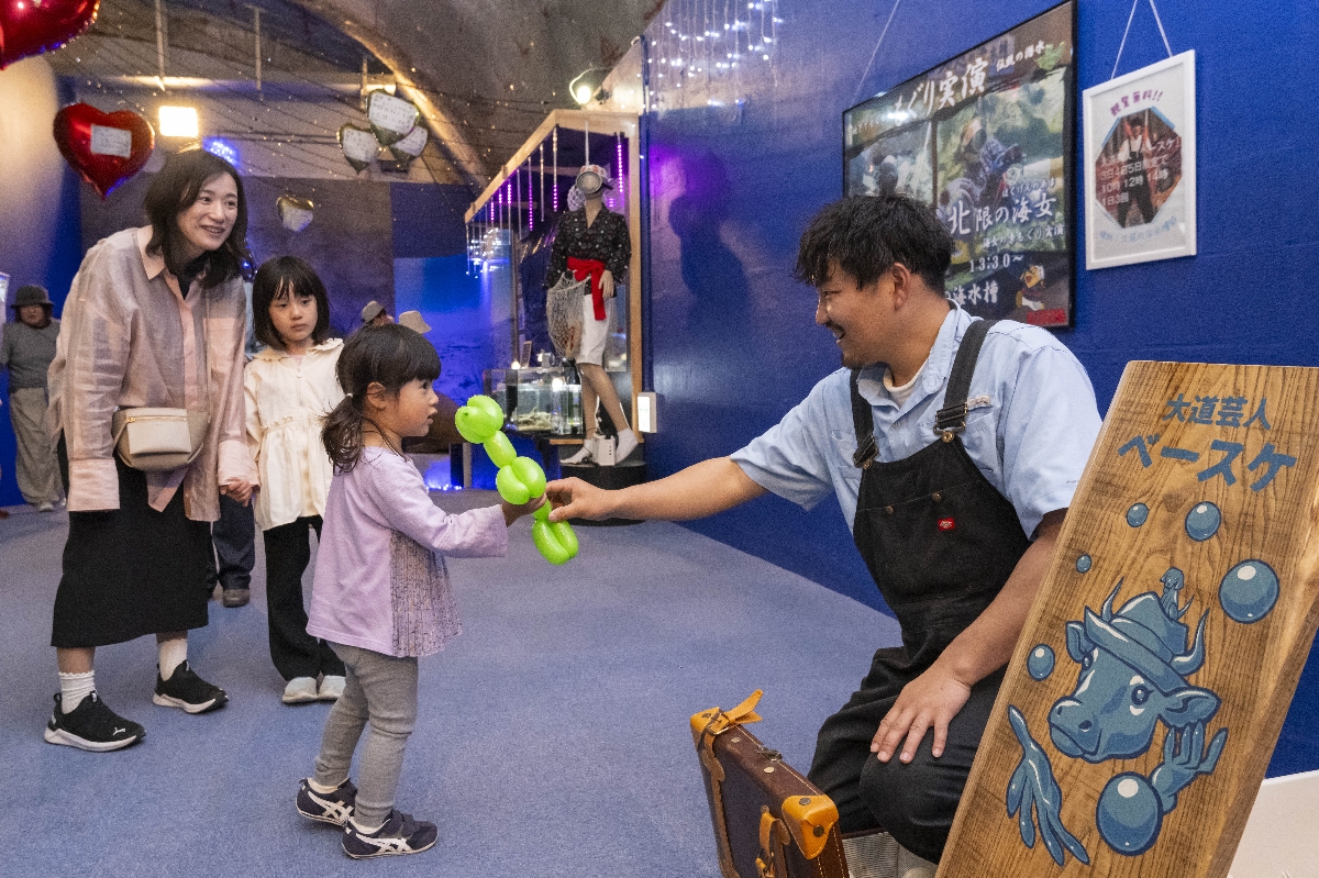 大道芸人からバルーンアートを受け取る子ども