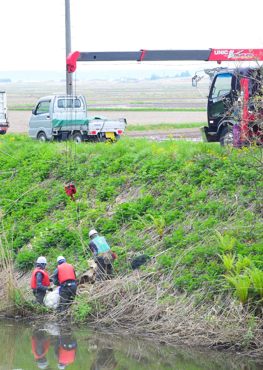 投棄されたおむつが入ったごみ袋を回収する作業員=8日、東北町