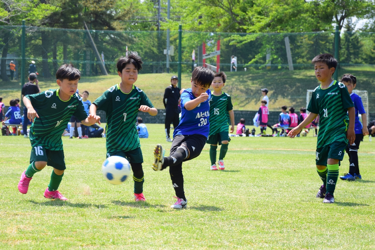 少年サッカー大会で元気にプレーする児童