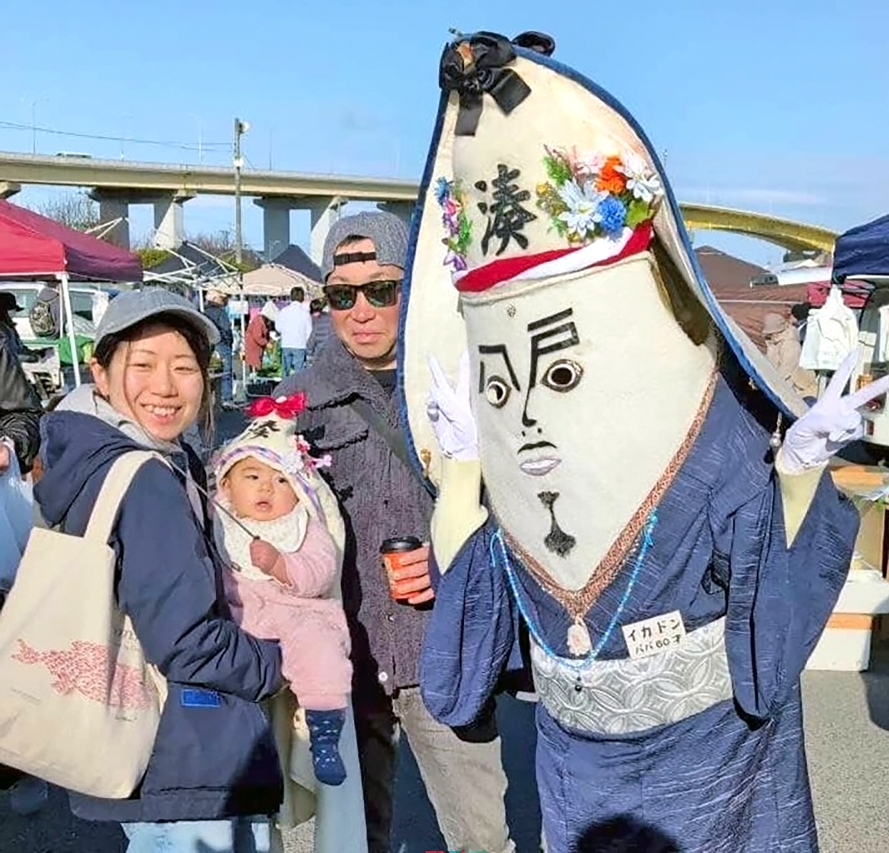 舘鼻岸壁朝市でイカドンパパと一緒に写真を撮る(左から)尾崎裕美さん、帆奏ちゃん、弘長さん