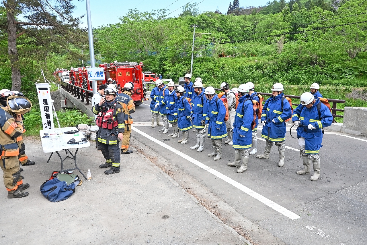 水のう袋を背負って鎮火作業に向かう消防団員=19日午前8時20分ごろ、南部町