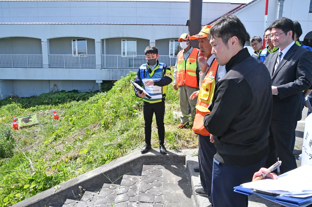 クマが出没したと想定し、現場で手順を確認する関係者=25日、むつ市役所