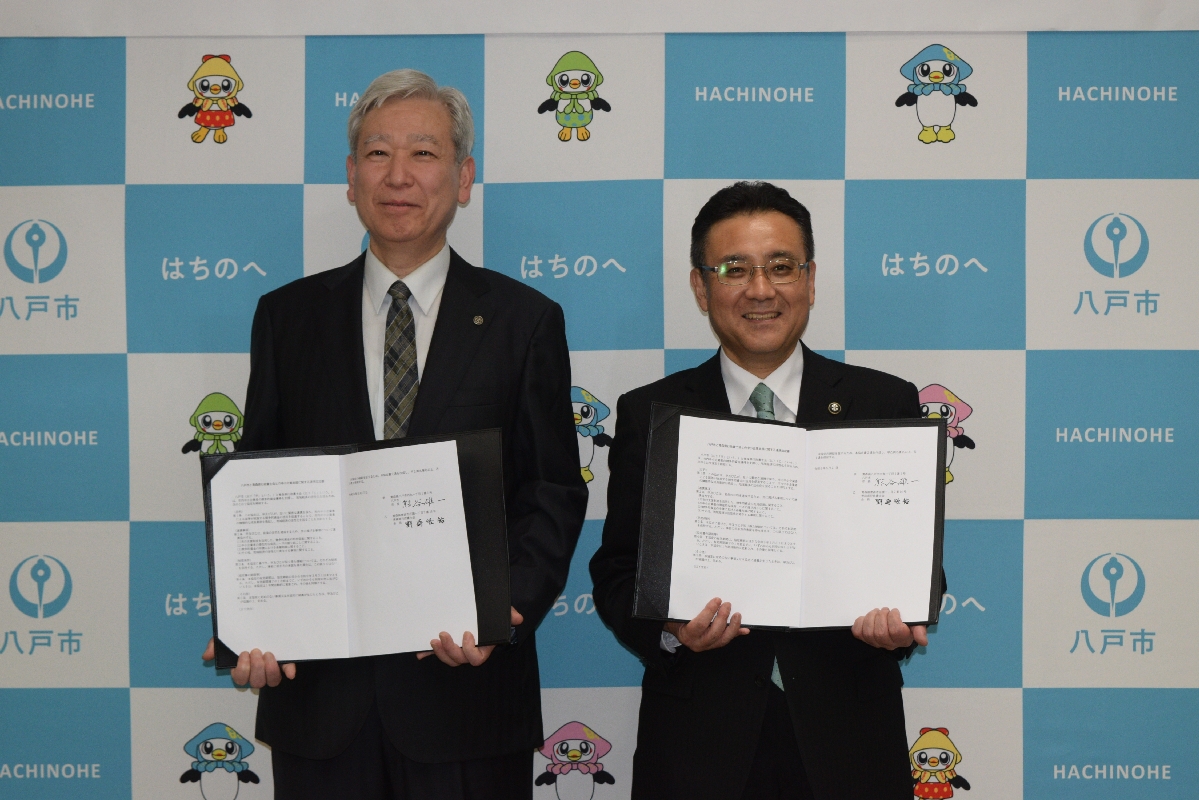 協定書を交わした熊谷雄一市長(右)と野崎径裕会長=27日、八戸市
