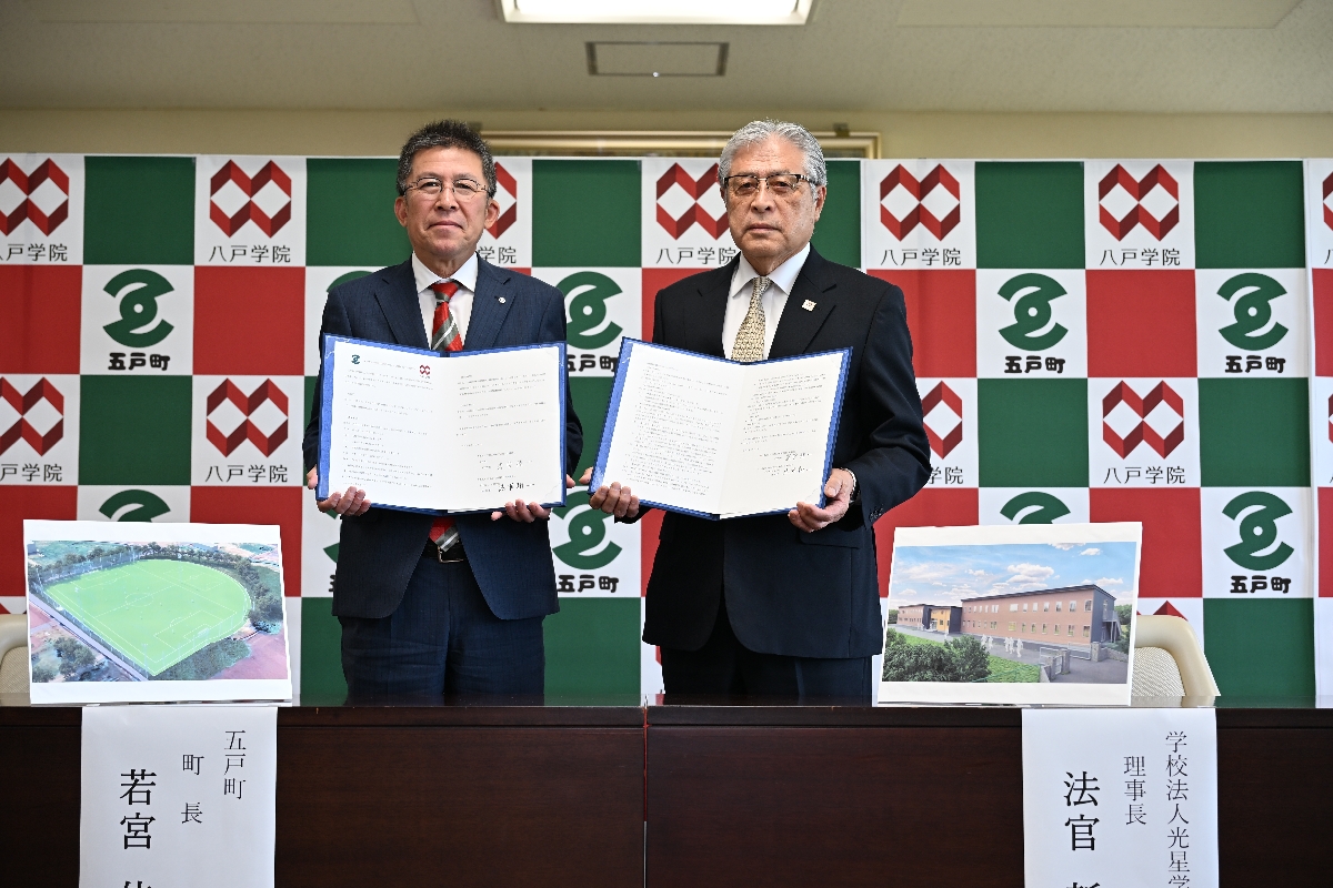 旧五戸高建物の無償譲渡に関する協定書に署名した若宮佳一町長（左）と法官新一理事長＝２７日、五戸町
