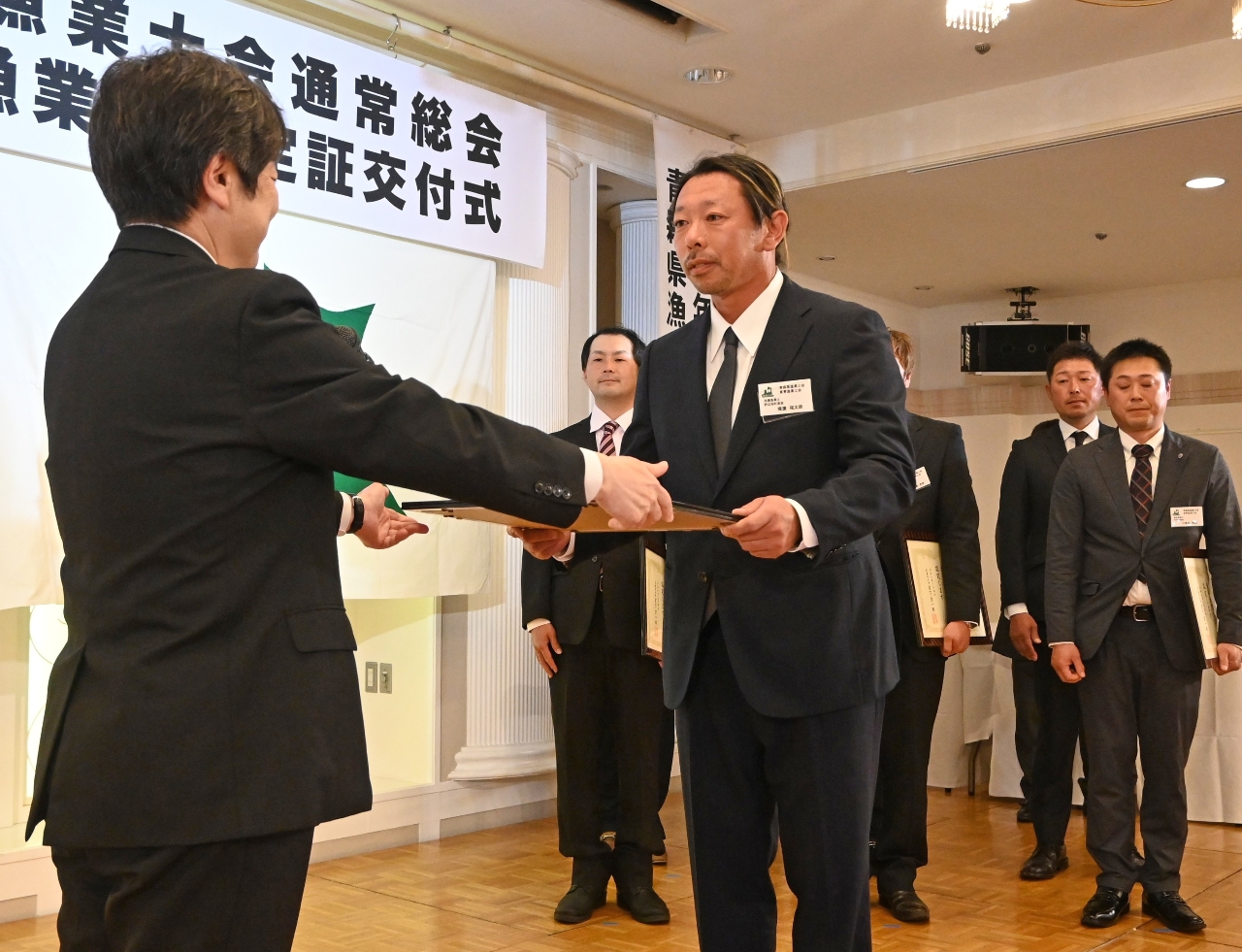 奥田忠雄副知事（左）から認定証を受ける横濵福太朗さん（中央）＝２７日、青森市内