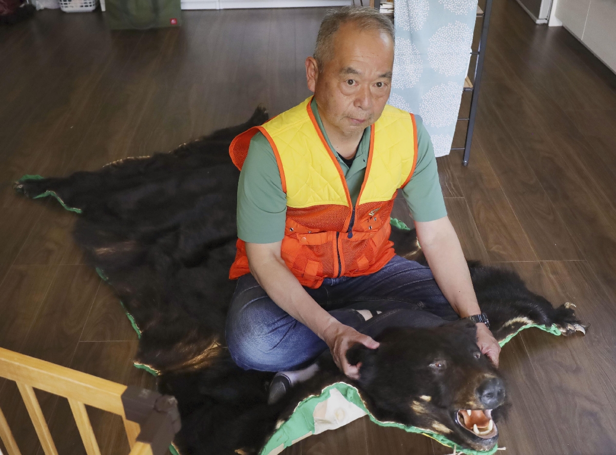 　過去に仕留めたクマの毛皮で作った敷物に座る舟山真人さん＝１４日、山形県小国町