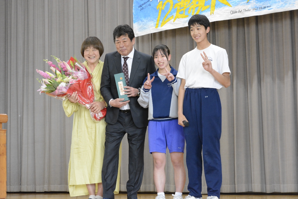 生徒との記念写真に収まる赤井英和さん(左から2人目)と妻の佳子さん(左)