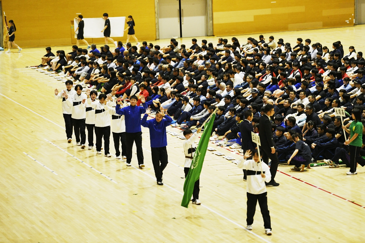 青森県高校総体の総合開会式で笑顔で手を振りながら入場行進する三沢＝５日、青森市マエダアリーナ