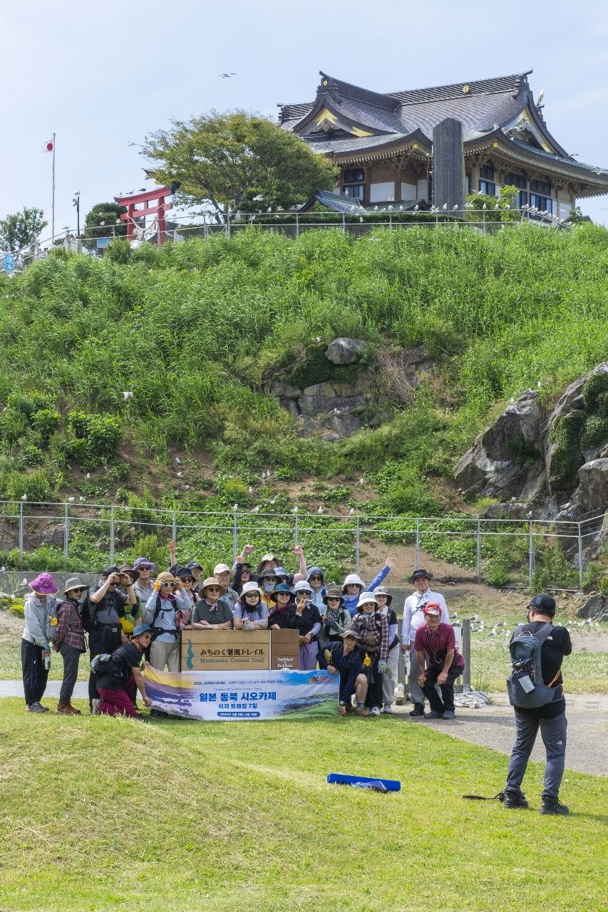 蕪島で写真撮影に臨む外国人観光客の団体。好調なインバウンドも観光の追い風となっている=12日、八戸市