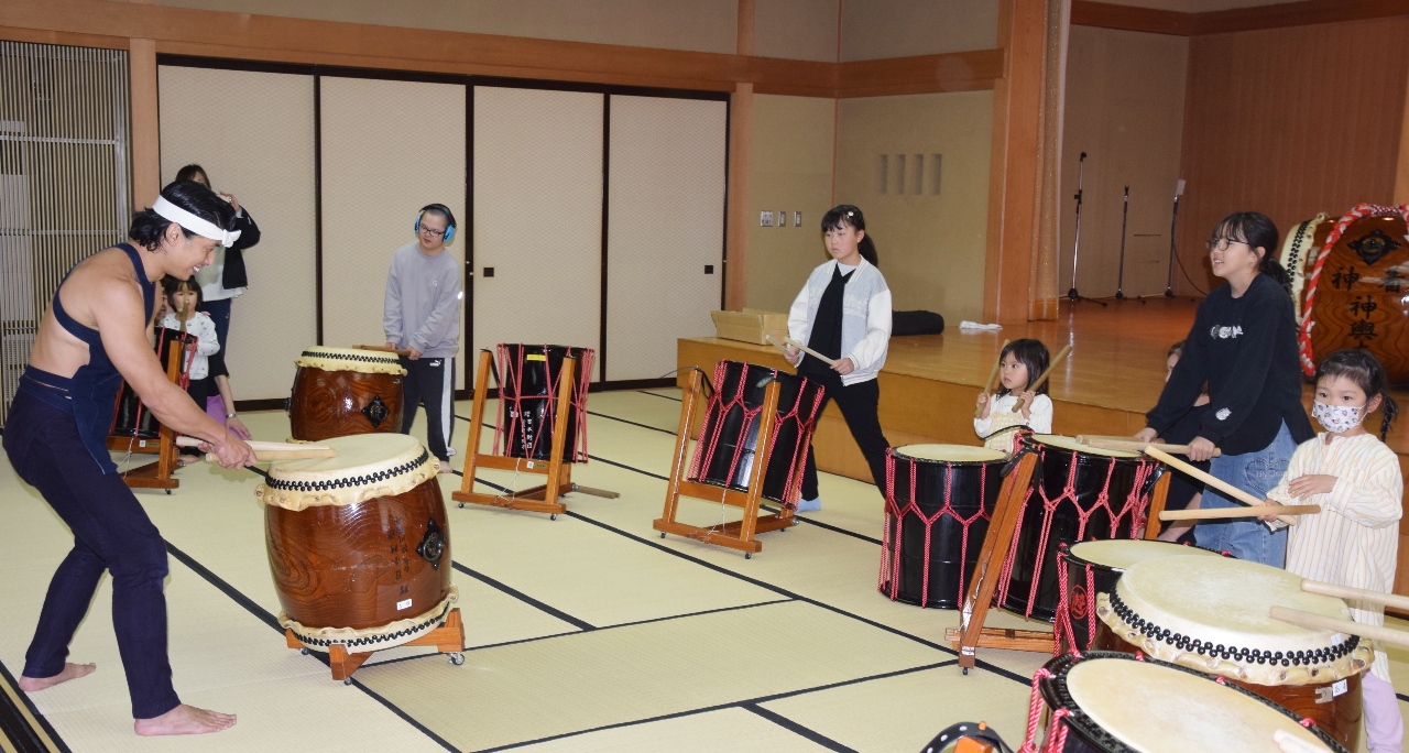 中込健太さん（左）からアドバイスを受けて太鼓をたたく子どもたち