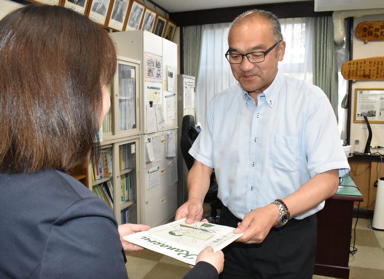 川口桂子局長(左)から「カナエルはちのへ」最新号を受け取る沼上進一校長=15日、八戸市