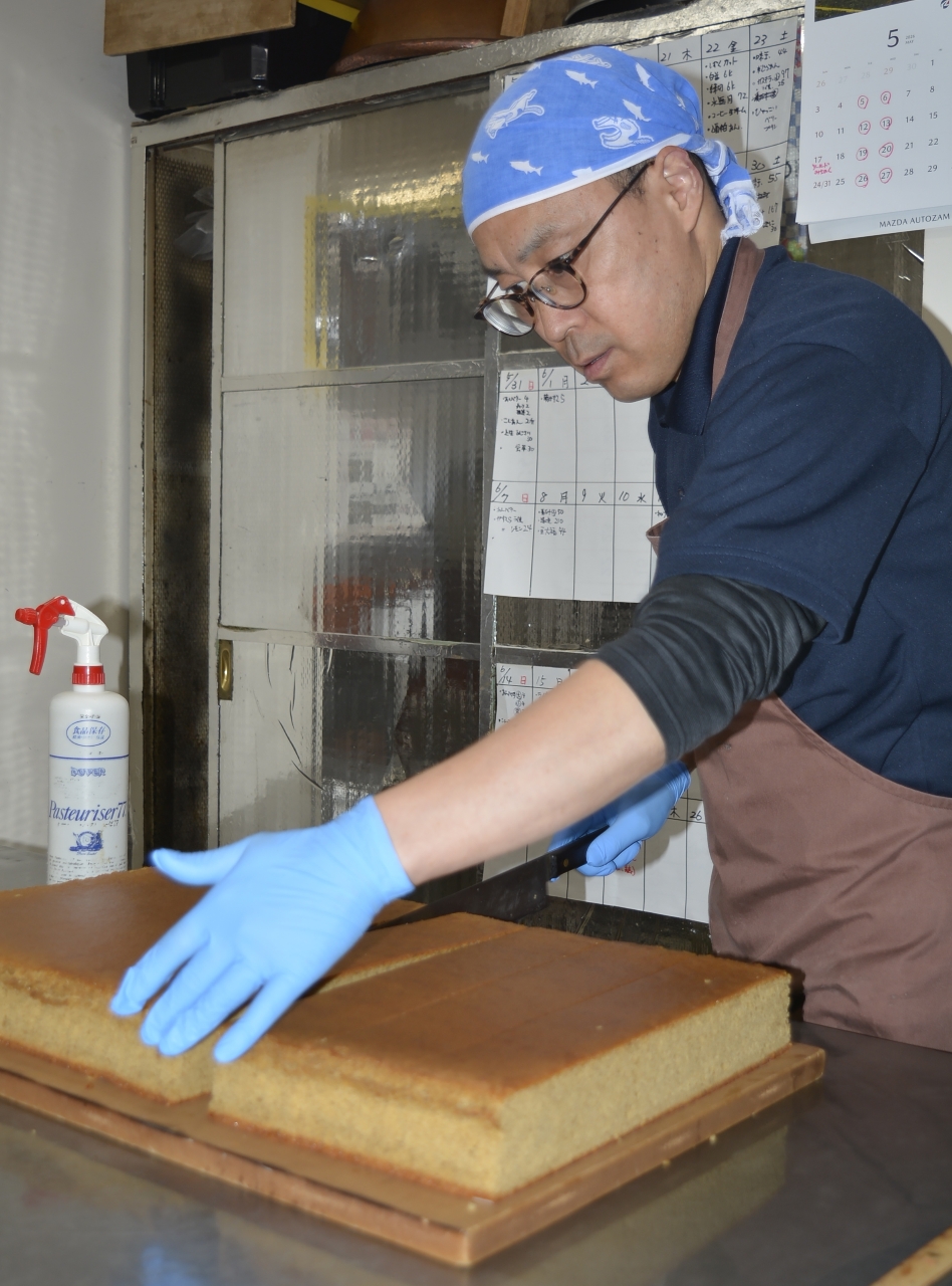 「ライ麦と甜菜糖のカステラ」をカットする舩場修店主=15日、八戸市