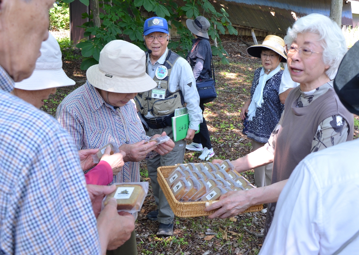 茨島のトチノキの実を使ったパウンドケーキを振る舞う小松良重さん(右)