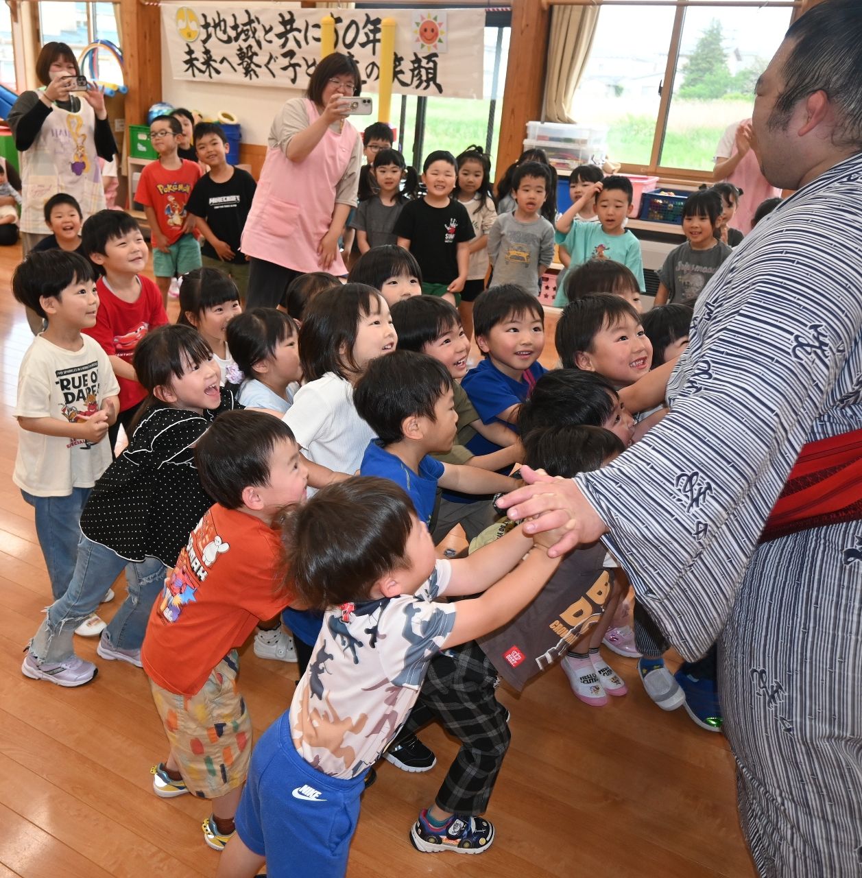 体重１８０キロの力士に束になって挑む門前保育園児＝１５日