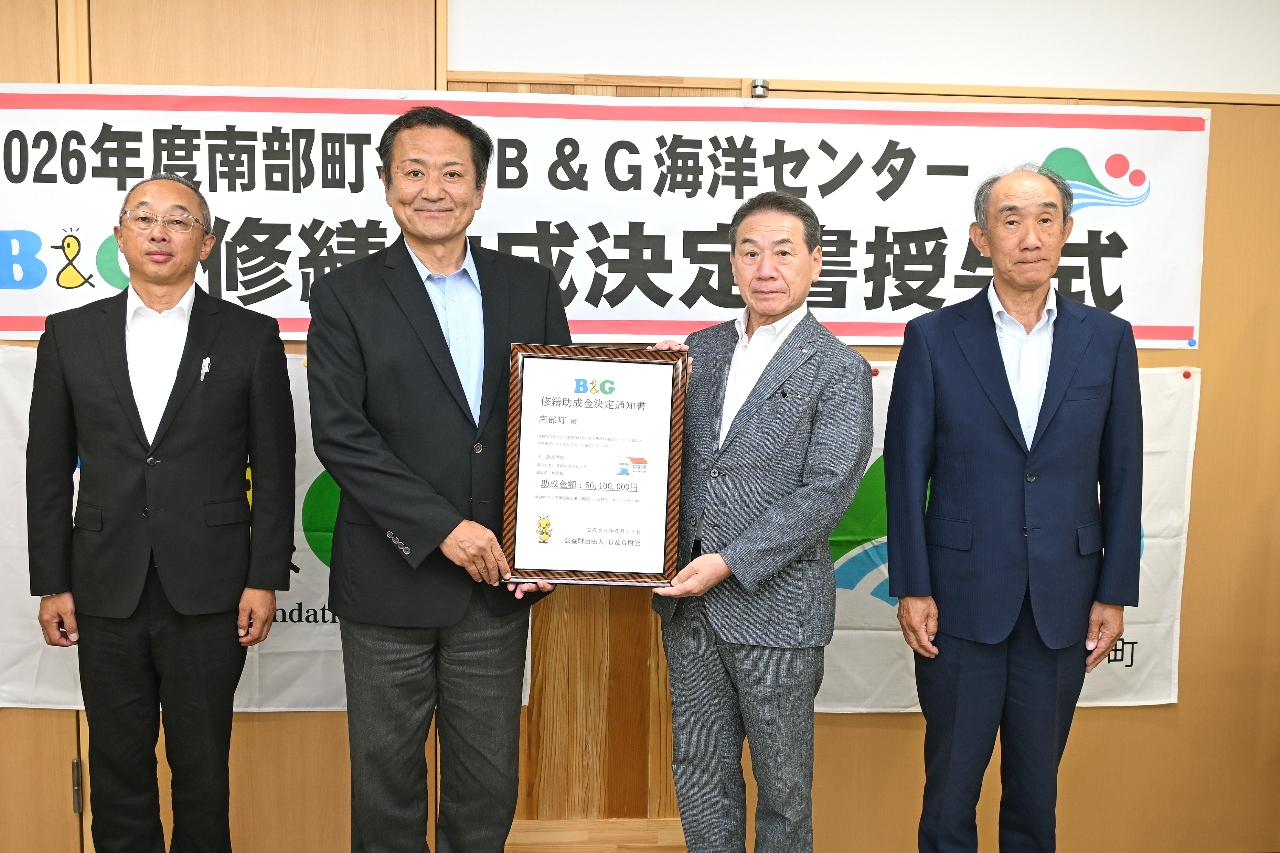 決定書を手にする菅原悟志理事長（左から２人目）