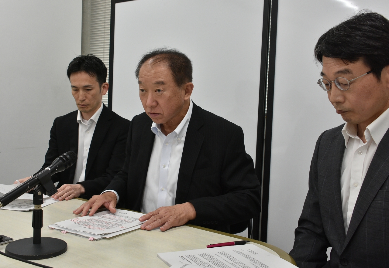 再処理の総事業費などについて説明する増田博武理事長(中央)=22日、青森県庁