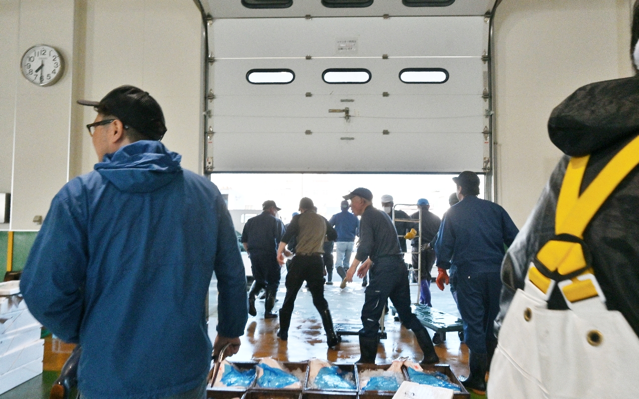 八戸市第2魚市場で競りを中断し場外へ避難する市場関係者=25日午前7時半ごろ