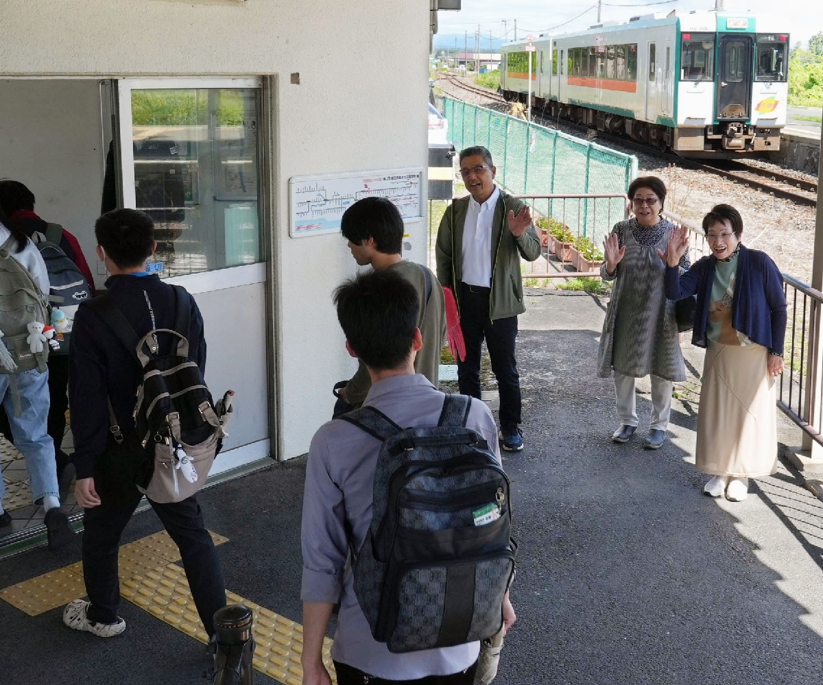 　通学のためＪＲ陸羽東線西古川駅に到着した留学生に声をかける高橋幸一さん（奥右から３人目）ら＝１０日、宮城県大崎市
