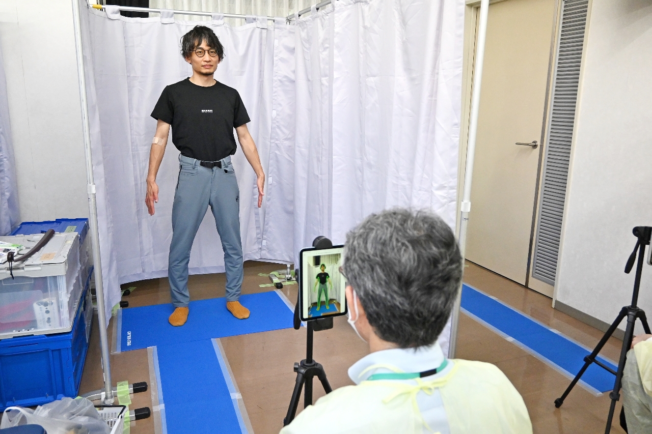 着衣のまま写真を撮影し、ＡＩで内臓脂肪の量などを測定する参加者＝６月上旬、弘前市