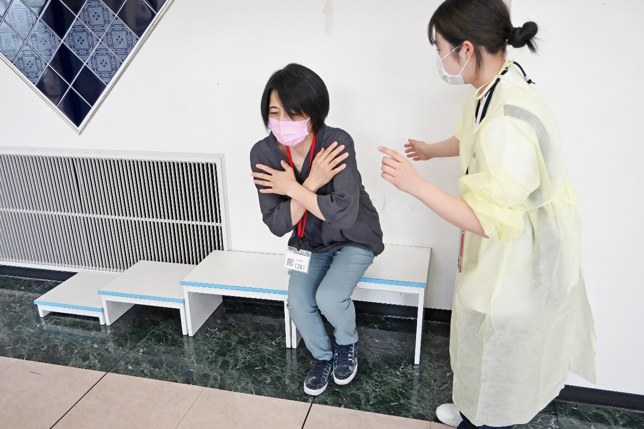座った状態から片足で立ち上がり、足の筋力を測定する参加者=6月上旬、弘前市